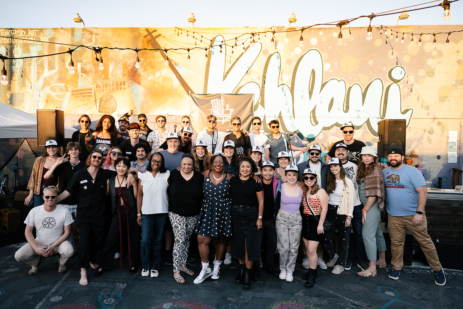 The Patiyochella volunteer crew posing together on stage at golden hour, 2025